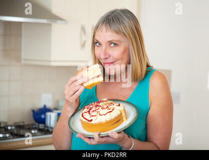 Donna di mangiare una crema pan di spagna Foto Stock