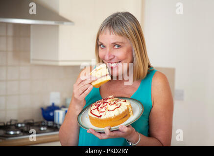 Donna di mangiare una crema pan di spagna Foto Stock