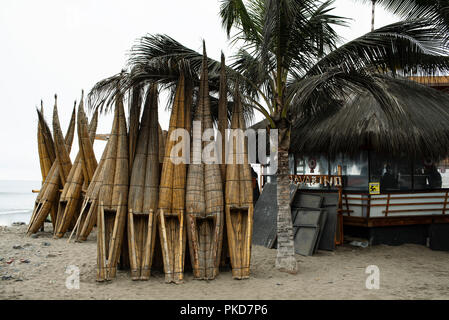 Totora reed barche (balsillas o caballitos - piccoli cavalli) allineati sulla spiaggia di Huanchaco. Regione di Trujillo, Perú. Lug 2018 Foto Stock
