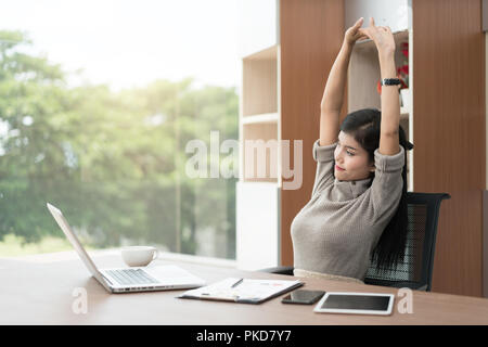 Giovani asiatici imprenditrice è rilassante in ufficio. Asian imprenditrice si allunga il suo corpo. Foto Stock