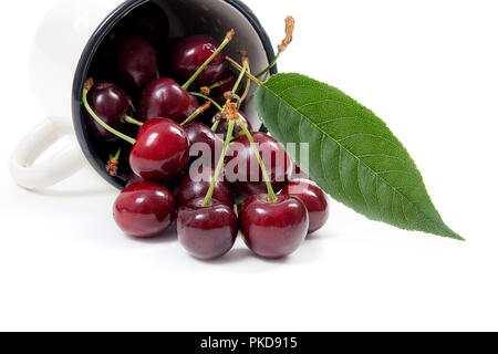 Tazza bianca con bacche mature di Rosso ciliegio dolce e diverse bacche nella parte anteriore della tazza. Composizione su uno sfondo bianco. Foto Stock