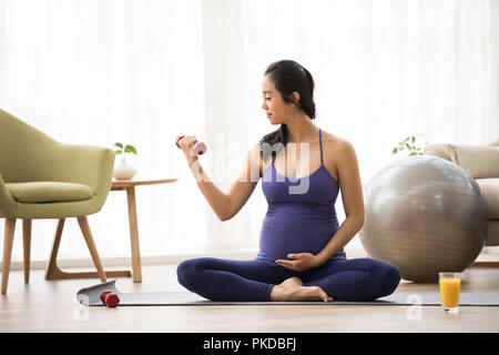 Allegra donna incinta che esercitano a casa Foto Stock