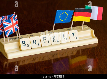 Lettere di Scrabble Brexit ortografia nel vassoio di Scrabble con britannica Union Jack e bandiera UE su mogano scuro dello sfondo Foto Stock