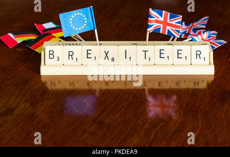 Lettere di Scrabble Brexiteer ortografia nel vassoio di Scrabble con britannica Union Jack Unione europea e la Germania bandiere su mogano scuro dello sfondo Foto Stock