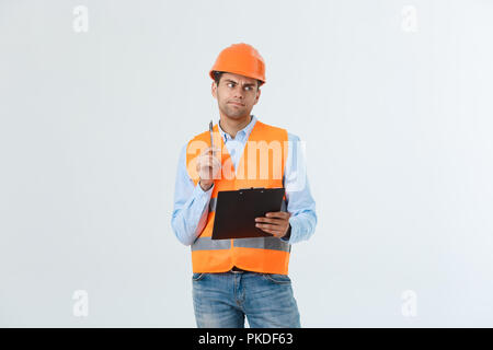 Ritratto di grave un architetto o un ingegnere di scrittura o di prendere appunti su una clipboard isolati su sfondo bianco Foto Stock