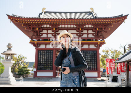 Bella asiatica visitatore navigando intorno e cercando di scattare foto in questa tradizionale giapponese del tempio. Foto Stock