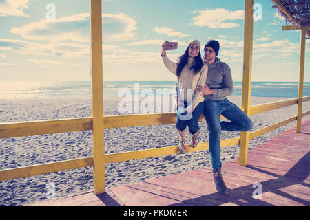 Molto felice coppia In amore tenendo Selfie sulla spiaggia in autmun giorno Foto Stock