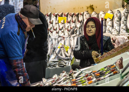 ISTANBUL, Turchia - 30 dicembre 2015: vecchia donna che indossa la sciarpa islamica l'acquisto di pesce nel mercato del pesce di Kadikoy, sul lato Asiatico. Pesce in ma Foto Stock
