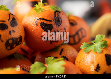 Primo piano di alcuni tangerini allestito come zucche intagliate con facce buffe Foto Stock