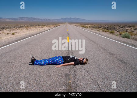 Donna adulta stabilisce in mezzo alla strada (Autostrada extraterrestre in Nevada il deserto). Concetto di audaci, Daredevil, osa, strada aperta Foto Stock
