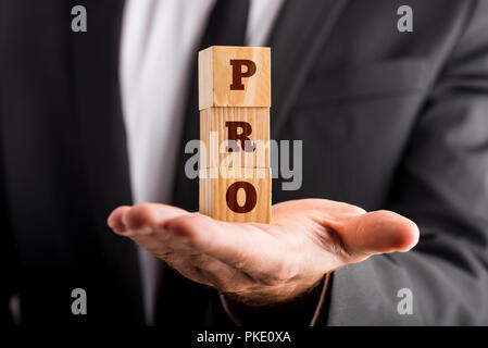 Imprenditore azienda tre cubi di legno accatastati sul palmo della sua mano la lettura di un segno PRO. Concettuale del professionalità e successo. Foto Stock
