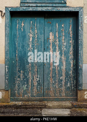 Sfald vernice blu su rustiche in legno porte doppie di edificio in Ariège Pirenei, Francia Foto Stock