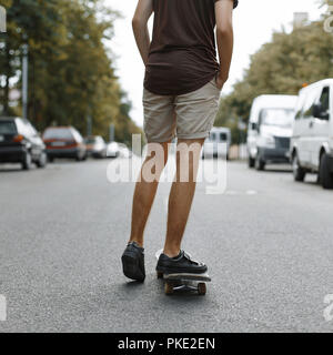 Uomo a cavallo su uno skateboard. Gambe su uno skateboard. Foto Stock