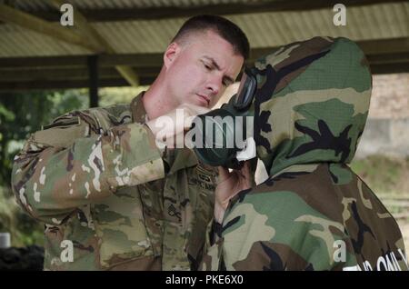 Il personale Sgt. Scott salmone, 540th Chemical Detatchment, 420th battaglione chimico, 96a comando di truppa, Washington Esercito Nazionale Guardia, aiuta un soldato malese con il quindicesimo Royal Reggimento Malay, durante l'esercizio Keris sciopero, luglio 24, 2018, il Camp Senawang, Malaysia. Malese e soldati degli Stati Uniti stavano lavorando insieme a insegnare e formare sulla base di procedure di decontaminazione. Foto Stock