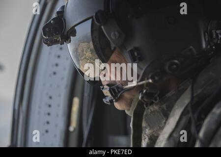 Stati Uniti Il personale dell'esercito Sgt. Glen Morgan, un capo equipaggio assegnato all'Idaho esercito nazionale della guardia aerea 183rd battaglione, guarda fuori dalla finestra di un UH-60 Black Hawk a Boise, Idaho, luglio 26, 2018. L'elicottero volò sulle colline della Valle del tesoro come parte di un tour di volo per i giovani nella Civil Air Patrol. Foto Stock