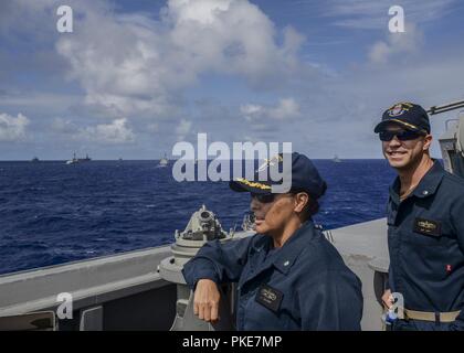 Oceano Pacifico (26 luglio 2018) della Cmdr. Claudine Caluori, sinistra, comandante della guidato-missile destroyer USS Sterett (DDG 104), e quella della Cmdr. Andrew Koy, Sterett il delegato (DDG 104), guarda la formazione di imprese multinazionali di navi nel mezzo di una foto esercizio durante il cerchio del Pacifico (RIMPAC) Esercizio, luglio 26. Venticinque nazioni, 46 navi, cinque sommergibili circa 200 aerei, e 25.000 personale partecipano RIMPAC dal 27 giugno al 2 agosto in e intorno alle Isole Hawaii e la California del Sud. Il più grande del mondo marittimo internazionale esercitazione RIMPAC fornisce una formazione unica opp Foto Stock