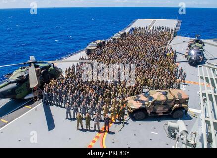 Oceano Pacifico (25 luglio 2018) militari membri dalla Royal Australian Navy, Esercito Australiano, U.S. Marines, Sri Lanka Navy Marines, Royal malese esercito, Sua Maestà delle Forze Armate di Brunei, Giappone terra Forza di Autodifesa e Nuova Zelanda esercito si riuniscono per una foto di gruppo sul ponte di volo dell'Atterraggio elicottero nave dock HMAS Adelaide (L01) durante il cerchio del Pacifico (RIMPAC) Esercizio, luglio 25. Venticinque nazioni, 46 navi, cinque sommergibili, circa 200 aerei e 25.000 personale partecipano RIMPAC dal 27 giugno al 2 agosto in e intorno alle Isole Hawaii e la California del Sud. Foto Stock