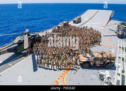 Oceano Pacifico (25 luglio 2018) militari membri dalla Royal Australian Navy, Esercito Australiano, U.S. Marines, Sri Lanka Navy Marines, Royal malese esercito, Sua Maestà delle Forze Armate di Brunei, Giappone terra Forza di Autodifesa e Nuova Zelanda esercito si riuniscono per una foto di gruppo sul ponte di volo dell'Atterraggio elicottero nave dock HMAS Adelaide (L01) durante il cerchio del Pacifico (RIMPAC) Esercizio, luglio 25. Venticinque nazioni, 46 navi, cinque sommergibili, circa 200 aerei e 25.000 personale partecipano RIMPAC dal 27 giugno al 2 agosto in e intorno alle Isole Hawaii e la California del Sud. Foto Stock