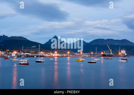 Città portuale mostrati in blu ora con barche di ormeggio e di luci di strada riflettendo in acqua; Ushuaia, Tierra del Fuego, Argentina Foto Stock