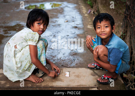Due giovani bambini giocando a carte in uno dei vicoli di Yangon; Yangon, Myanmar Foto Stock