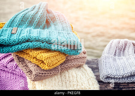 Bellissimo sfondo inverno maglia blu e giallo molto hat. Uncinetti fatti a mano. Close-up di cappelli di maglia di colore blu, giallo, rosa e bianco Foto Stock