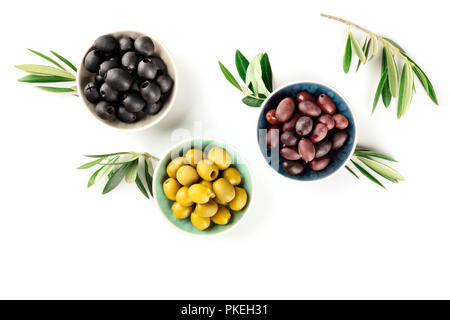 Un overhead foto di vari olive in ciotole con foglie e copia spazio su uno sfondo bianco Foto Stock