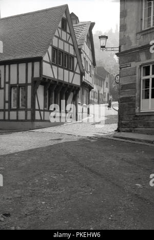 1950, storica, Colonia, Germania, una strada acciottolata nella città vecchia che mostra all'angolo uno dei suoi antichi edifici in legno. Foto Stock