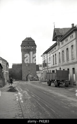 Degli anni Cinquanta, storico, Colonia, Germania, un rimorchio parcheggiato in una strada con una torre e ingresso alla città vecchia. Foto Stock