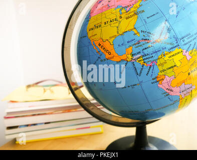 I paesi e i continenti da vicino con la mappa a colori su un globo con libri in background. Istruzione e concetto di viaggio. Foto Stock