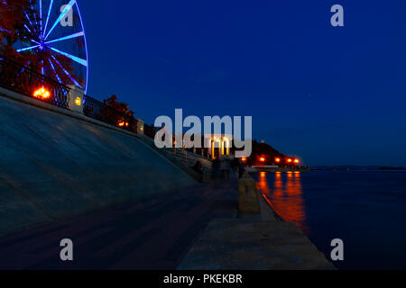 Ruota panoramica sulle rive del fiume Amur a Khabarovsk contro il cielo di notte. Un brillante illuminazione. Fotografato a lunga esposizione. Foto Stock