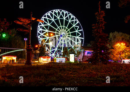 Ruota panoramica sulle rive del fiume Amur a Khabarovsk contro il cielo di notte. Un brillante illuminazione. Fotografato a lunga esposizione. Foto Stock