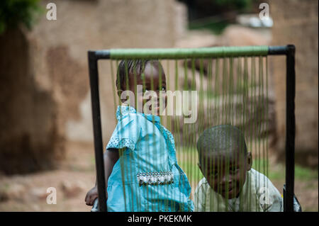 Mali, Africa - circa agosto 2009 - africano nero bambini divertirsi con una sedia in plastica al di fuori di casa che vive in una zona rurale vicino a Bamako Foto Stock