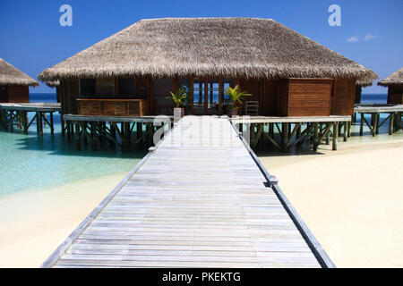 Il molo di legno che conducono a bungalow Overwater sull Oceano Pacifico nelle Maldive Foto Stock