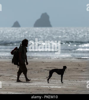 Uomo e cane a camminare sulla spiaggia in Cornovaglia Foto Stock