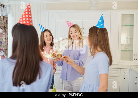 Un gruppo di amiche con una torta con candele di celebrare un birt Foto Stock