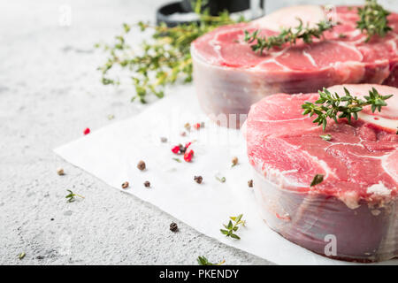 Freschi Stinco di vitello fette di carne di manzo per osso buco per la cottura sul tagliere con ingredienti e condimenti timo, pepe, sale. Foto Stock