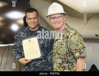 NEWPORT NEWS, Va. (30 luglio 2018) della nave 2 Veteran Class Dereck S. Lindburg, da Manila, Filippine, assegnato alla USS Gerald Ford (CVN 78) dipartimento di alimentazione, riceve il suo certificato di nomina da Capt. Richard McCormack, Ford comandante, durante un avanzamento meritoria cerimonia nella nave carica di alimentazione. Foto Stock