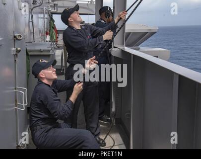 Oceano atlantico (31 luglio 2018) Quartermaster marinaio apprendista Christopher Mynhier, da Yuba City, California, sinistra, assegnato alla portaerei USS George Washington (CVN 73), Intendente di terza classe Kole strimpellare, da Rapids, Wisconsin, sollevare il foxtrot flag che indica ala fissa le operazioni di volo a bordo della portaerei USS George H.W. Bussola (CVN 77). Mynhier è temporaneamente assegnato a GHWB mentre la nave è in corso la routine di conduzione di attività di allenamento per mantenere la disponibilità del gestore. Foto Stock