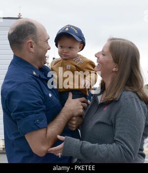 Chief Petty Officer James Maida, un nostromi mate a bordo del guardacoste Alex Haley (WMEC 39), saluta la sua famiglia dopo la taglierina ormeggiato al suo homeport di Kodiak, Alaska, 1 agosto 2018. I membri di equipaggio del Alex Haley restituito da 90 giorni di pattugliamento di distribuzione più di 16.000 miglia per tutto l'Oceano Pacifico. Stati Uniti Coast Guard Foto Stock