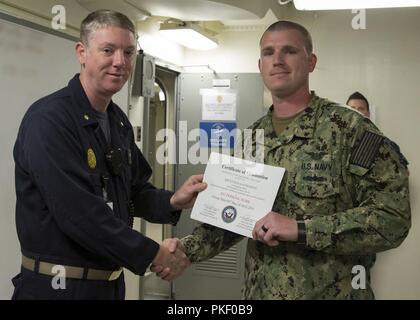 NEWPORT NEWS, Va. (Agosto 3, 2018) Aviation Supporto tecnico di attrezzature di prima classe e Mark Perkins, da Virginia Beach,Virginia, assegnato alla USS Gerald Ford CVN (78) intermedio di aeromobili al reparto manutenzione, riceve un certificato di laurea da Lt. La Cmdr. Fred Masten, Ford security officer, durante un in-port security force (ISF) Classe di laurea. Ventinove i marinai si è laureato tre settimane di corso ISF. Foto Stock