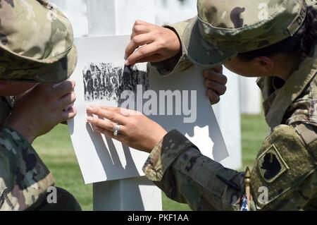 Con l'aiuto del suo compagno di Oklahoma Esercito Nazionale guardie, Staff Sgt. Ashley Delisle, membro awards manager, sfrega una copia della lapide di suo prozio, Pvt. 1. Classe Anton J. Reida, all'Oise-Aisne Cimitero Americano, Fere-En-Tardenois, Francia, 27 luglio. Reida fu ucciso durante la guerra sul campo di battaglia di Aisne-Marne, Sett. 1, 1918. Soldati provenienti da unità che comprendeva la XLII divisione di fanteria durante la prima guerra mondiale, ha partecipato alla seconda fase di un anno di WWI commemorazione centenaria in tutta la Francia settentrionale da luglio 24 - 29. Foto Stock