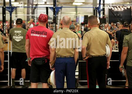 Brian Chontosh, Marine veterano e CrossFit Livello Uno membro dello staff, Lt. Col. John Caldwell, direttore del marketing e della comunicazione per Marine Corps il reclutamento di comando e il Mag. Gen. James W. Bierman Jr., comandante generale dei Marine Corps il reclutamento di comando, guarda una dimostrazione di allenamento durante il 2018 Reebok CrossFit Games a Madison, Wisconsin, 2 agosto 2018. Il CrossFit Games è il mondo del test di Premiere per trovare il "più forti sulla terra." I giochi si sono svolti ogni estate dal 2007 e includono una vasta gamma di diversi eventi che concentrarsi sui movimenti funzionali per spostare velocemente Foto Stock