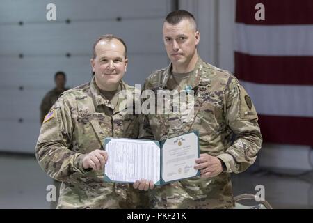 Col. Peter Mondelli, 297sostegno regionale comandante del gruppo, presenta l'esercito encomio medaglia al cap. Timothy Cooper, 297SC commander, durante l'unità di disattivazione il Agosto 5, 2018 in Alaska National Guard Armory su base comune Elmendorf-Richardson. Foto Stock