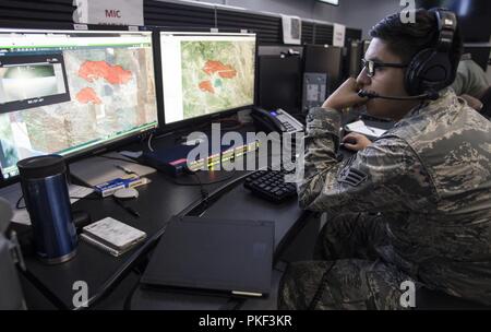 Stati Uniti Air Force Senior Airman Michael Chacon della 163d Operations Support Squadron, 163d attacco ala, California Air National Guard, guarda a un incendio mappa per il complesso di Mendocino Fire, e il Agosto 4, 2018 mentre si lavora in un centro operativo a marzo riserva d'aria di base, California. Chacon e altri membri dell'ala sta lavorando con agenzie di stato per fornire fuoco perimetro scansioni e controlli in loco all'interno del complesso di masterizzare area, che comprende sia il fiume e Ranch incendi. Foto Stock