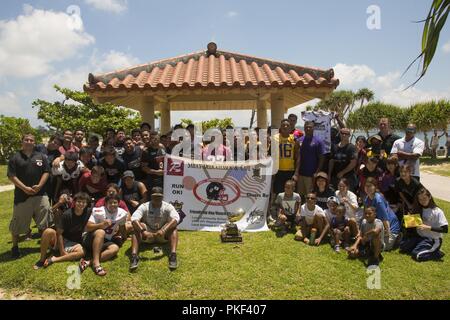 CHATAN, Okinawa, in Giappone - i membri degli STATI UNITI Le forze del Giappone - American Football League posano per la foto durante una giornata di amicizia beach cleanup 4 Agosto sulla Sunset beach seawall in Chatan, Okinawa, in Giappone. Il USFJ - AFL è stato avviato nella speranza che gli enti locali e la comunità militare potrebbe trovare un interesse comune e di costruire solide relazioni di amicizia. Il cleanup ammessi giocatori da tutte le squadre di trascorrere del tempo insieme fuori dal campo di calcio e di lavorare insieme per prendersi cura della loro comunità. Foto Stock