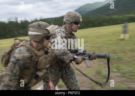 Stati Uniti Marine Corps Cpl. Gary Denson, destra, assegnato a Charlie Company, 1° Battaglione, ventitreesimo reggimento Marine, corre al suo prossimo punto cottura sotto la supervisione di Sgt. Clinton Graebner, sinistra, durante la conduzione di un live-fire stress evento riprese durante la quarta divisione Marine Super Squad concorso a base comune Elmendorf-Richardson, Alaska, il 6 agosto 2018. Durante il multi-giorni di gara, le squadre da 1 ° e 3 ° battaglioni, ventitreesimo reggimento Marine e 1° Battaglione, xxiv reggimento Marine, esercitato la loro tecnica e tattica abilità dal competere in eventi che offensiva evidenziato/def Foto Stock