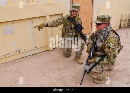 Da sinistra, U.S. Army Sgt. Donald Montgomery e Sgt. David Curry, entrambi i fanti assegnato al primo plotone, 2° plotone, la società C, 2° Battaglione, 137Reggimento di Fanteria, 155Armored Brigade Combat Team, Kansas Esercito Nazionale Guardia, discutere i movimenti durante la conduzione di squadra formazione situazionale esercizio prove presso l'esercito Comando Centrale Readiness Training Center, Camp Buehring, Kuwait, il 7 agosto, 2018. Il 2-137 IN è distribuito in Kuwait a sostegno del funzionamento Spartan scudo. Foto Stock