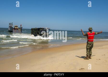 VIRGINIA BEACH, Va. (26 luglio 2018) un marinaio da unità Beachmaster (BMU) 2 guide un U.S. Esercito il veicolo su Utah Beach dopo la partenza da un assalto unità artigianali (ACU) 2 Landing Craft Utility (LCU) 1600 onboard Expeditionary Comune Base Little Creek - Fort Story durante il Tridente Sun 18 esercizio. Trident Sun 18 è un preposizionamento marittima forza (MPF) operazione destinata a fornire una formazione alla componente di riserva personale per quanto riguarda il flusso in offload di veicoli e attrezzature militari. Foto Stock