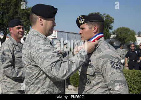 Stati Uniti Air Force Col. Thomas Miner, le forze di sicurezza Gruppo commander, luoghi una medaglia attorno al collo di tecnico Sgt. Cory Irvin, 37th Supporto Training Squadron combat arms formazione e manutenzione di istruttore, come egli è selezionato per l'aria di istruzione e di formazione del comando Defender Challenge team Luglio 27, 2018 a base comune San Antonio-Randolph, Texas. Defender sfida è una delle forze di sicurezza La concorrenza che box squadre gli uni contro gli altri in armi realistiche, le operazioni di smontaggio del relè e sfida gli eventi. Foto Stock