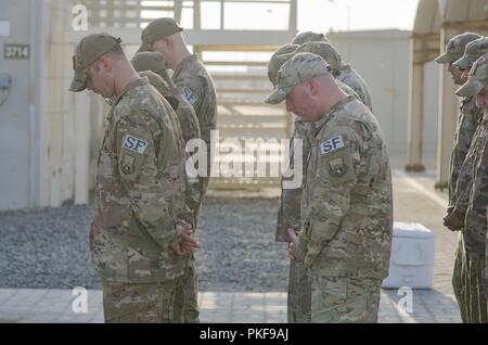 380 Le forze di sicurezza membri bow le loro teste nel rispetto dei caduti i membri del servizio durante una cerimonia di ritiro al Dhafra Air Base 3 Agosto, 2018. L'aria 380 Ala Expeditionary onori caduti i membri del servizio una volta al mese durante la cerimonia. Foto Stock